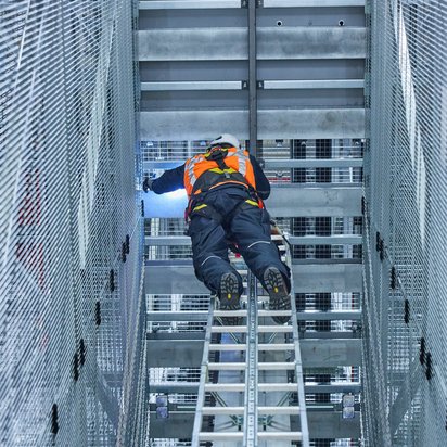 Lees over meer keuringen en inspecties. Inspecteur voert een veiligheidsinspectie uit in een magazijn met hoge stellingen.